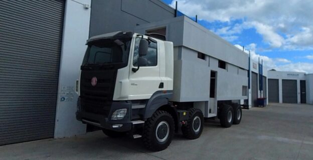 8x8 Camper Truck in front of warehouse